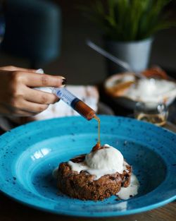 Close-up of person pouring syrup from syringe on cake