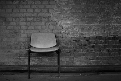 Close-up of chair against brick wall