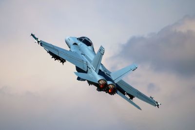 Low angle view of airplane flying in sky during sunset