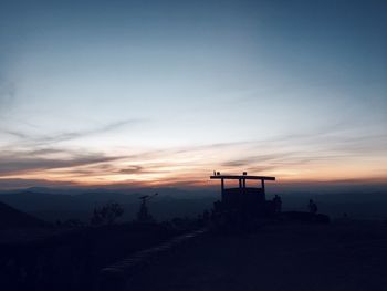 Silhouette cross against sky during sunset