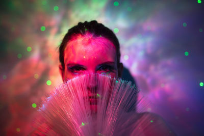 Portrait of beautiful young woman against illuminated background