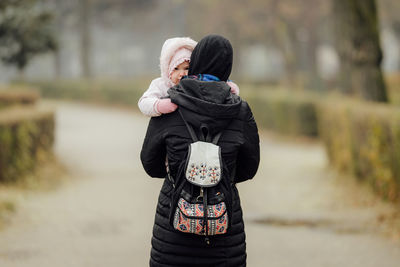 Rear view of mother with child during winter