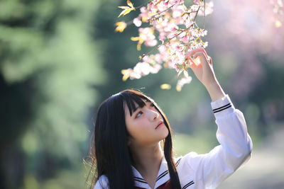 Portrait of woman with pink flowers against blurred background