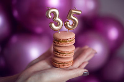 Woman's hand with manicure holding cookies with candles numbers 35