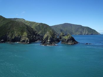 Scenic view of rock formations in calm sea against clear sky