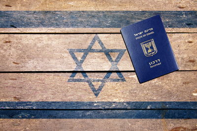 Directly above shot of passport on painted israeli flag wood