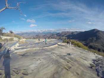 People on salt pan on mountain against sky