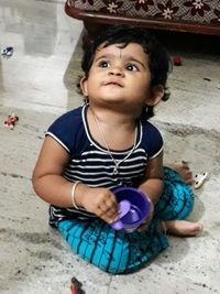 Portrait of cute baby girl looking away while sitting on floor