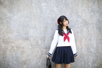 Young woman standing against wall outdoors