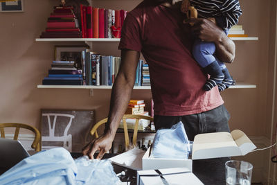 Midsection of businesswoman with male toddler working at home