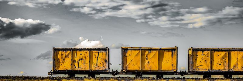 Yellow train on factory against sky