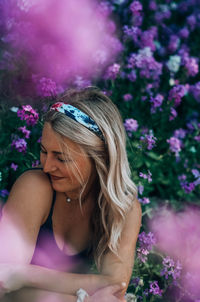 Midsection of woman sitting on purple flowering plant