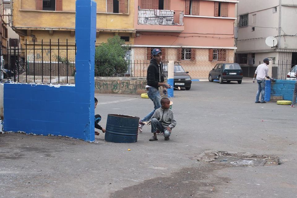 real people, building exterior, architecture, built structure, three people, day, outdoors, street, full length, transportation, men, childhood, lifestyles, togetherness, land vehicle, boys, helmet, scooter, city, adult, people