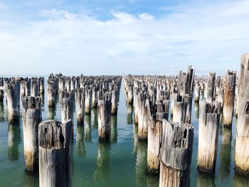 Panoramic view of wooden posts in sea against sky