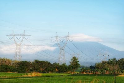 Electricity pylon on field against sky