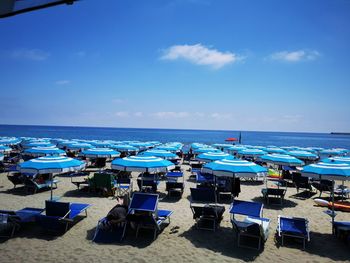 Chairs on beach against blue sky