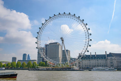 Ferris wheel in city against cloudy sky