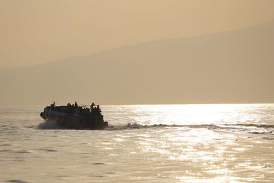 Silhouette boat in sea against clear sky during sunset