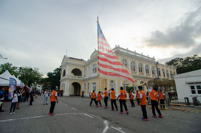 People walking in front of building against sky