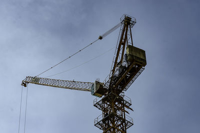 Low angle view of crane at construction site against sky