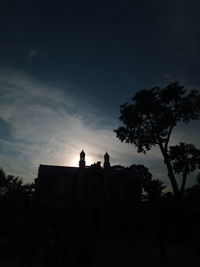 Low angle view of silhouette trees and buildings against sky at sunset