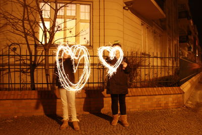 Full length of man standing in illuminated light at night