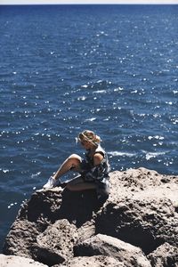 Man sitting on rock at beach