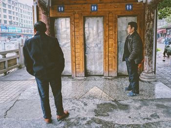 Rear view of man standing by building in city