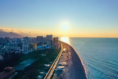 Scenic view of sea by buildings against sky during sunset