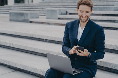 Man using mobile phone while sitting on staircase