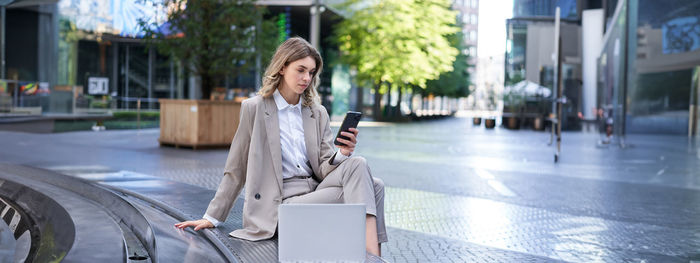 Portrait of young woman standing in city