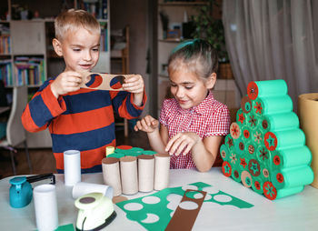 Cute girl and boy preparing christmas decoration at home