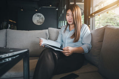 Young woman sitting on sofa at home