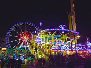 Illuminated ferris wheel against clear sky at night