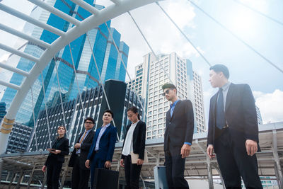 Businesspeople standing on bridge against buildings in city
