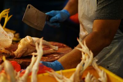 Midsection of butcher cutting meat on table