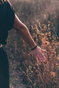 Cropped hand of woman against plants