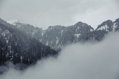 Scenic view of clouds covering mountains during winter