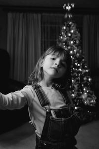 Portrait of girl standing by christmas tree at home