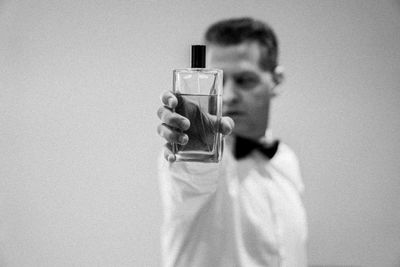 Midsection of man drinking glass against white background