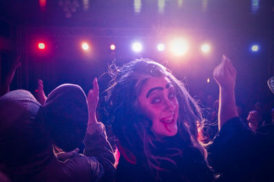 Portrait of young woman amidst crowd in concert