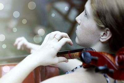 Close-up side view of teenage girl playing string instrument