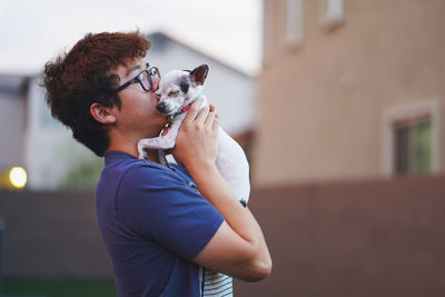 Side view of young man kissing dog