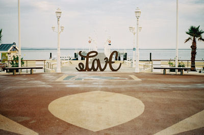 Information sign on table by sea against sky