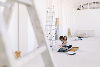 A young couple in love have moved into a new house and are making repairs painting white walls