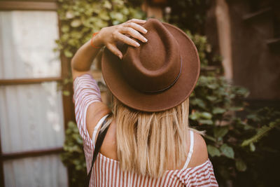 Back view of adventurous traveler touching her hat in the nature