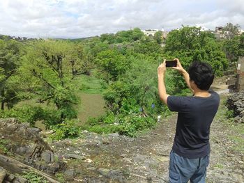 Rear view of man photographing trees