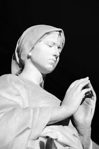 Low angle view of old statue against black background