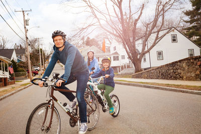 Cheerful family riding bicycle on road