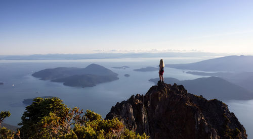 Man standing on rock against sky